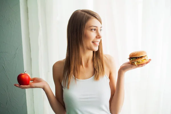 Régime alimentaire. Le concept d'une alimentation saine et malsaine. Le modèle plus la taille fait un choix en faveur de la nourriture saine et les fruits en refusant la restauration rapide et hamburger — Photo