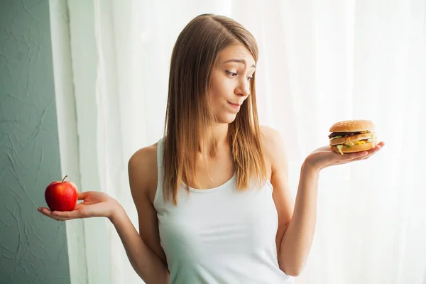 Régime alimentaire. Le concept d'une alimentation saine et malsaine. Le modèle plus la taille fait un choix en faveur de la nourriture saine et les fruits en refusant la restauration rapide et hamburger — Photo