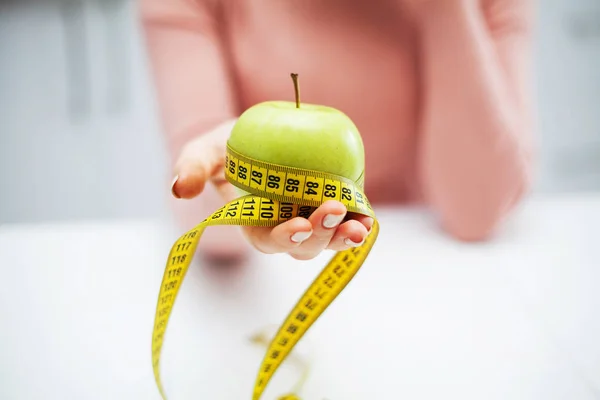 Dieta y salud. Manzana verde y cinta de centímetro en manos femeninas —  Fotos de Stock