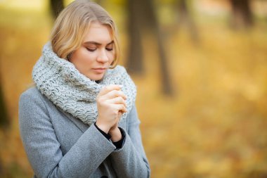 Soğuk algınlığı ve grip. Sonbahar park ve el donmuş sıcak yürüyüş gri paltolu genç kadın