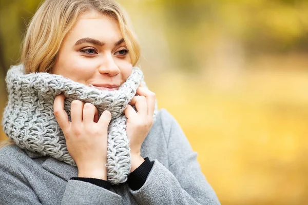 Erkältung und Grippe. junge Frau im grauen Mantel spaziert durch den Herbstpark und wärmt gefrorene Hand — Stockfoto