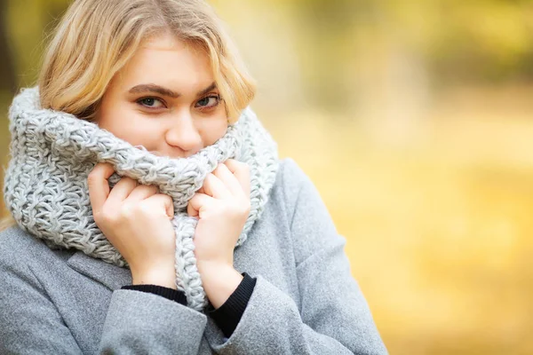 Erkältung und Grippe. junge Frau im grauen Mantel spaziert durch den Herbstpark und wärmt gefrorene Hand — Stockfoto