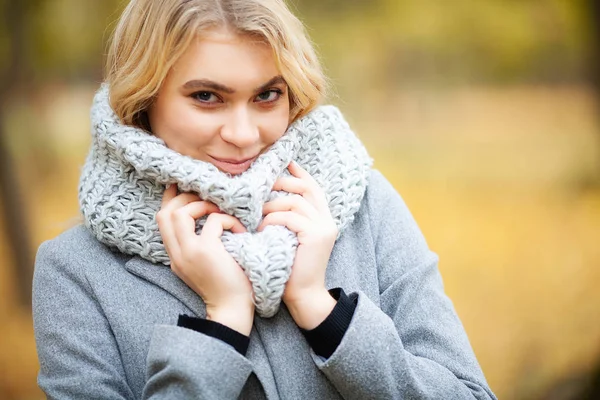 Frio e gripe. Jovem mulher em um casaco cinza andando no parque de outono e aquece a mão congelada — Fotografia de Stock