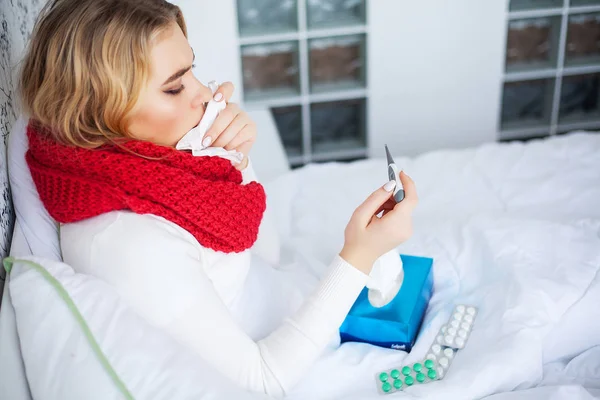 Frau mit Grippevirus liegt im Bett und misst ihre Temperatur mit Thermometer — Stockfoto