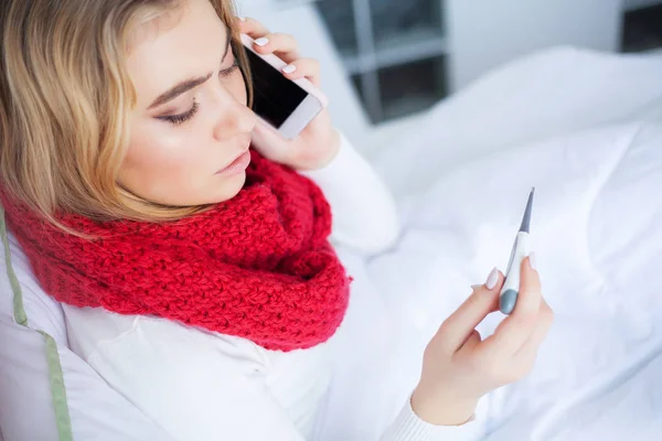 Wanita dengan virus flu terbaring di tempat tidur, dia mengukur suhu tubuhnya dengan termometer — Stok Foto