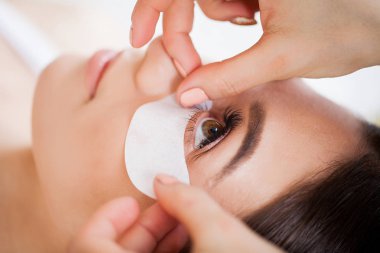 Kirpiklerini uzat. Sahte kirpikler. Kirpik uzatma prosedürü. Profesyonel stilist, kadın kirpiklerini uzatıyor. Usta ve bir müşteri güzellik salonunda.