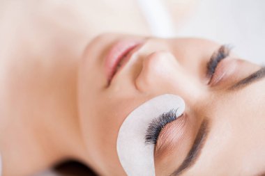 Kirpiklerini uzat. Sahte kirpikler. Kirpik uzatma prosedürü. Profesyonel stilist, kadın kirpiklerini uzatıyor. Usta ve bir müşteri güzellik salonunda.