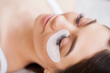 Kirpiklerini uzat. Sahte kirpikler. Kirpik uzatma prosedürü. Profesyonel stilist, kadın kirpiklerini uzatıyor. Usta ve bir müşteri güzellik salonunda.