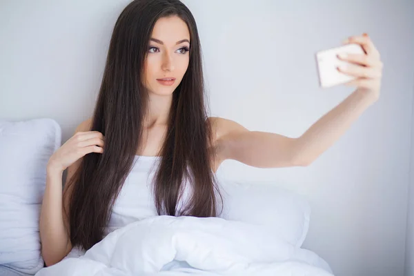 Shot of Happy linda mujer se encuentra en la cama usando el teléfono móvil — Foto de Stock