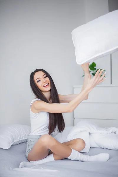 Care Concept. Een mooie jonge brunette lachende vrouw liggend in witte bed, comfortabel en zalig — Stockfoto