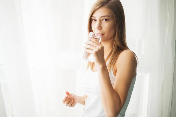 Conceito de saúde. Jovem mulher segurando pílula e copo de água — Fotografia de Stock