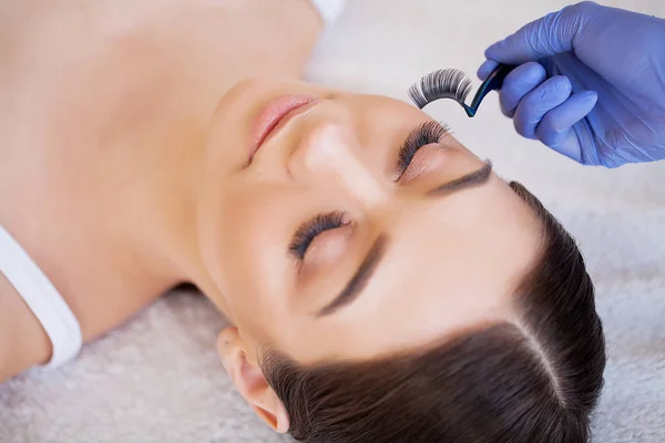 Extensiones de pestañas. Pestañas falsas. Procedimiento de extensión de pestañas. Estilista profesional que alarga las pestañas femeninas. Maestro y un cliente en un salón de belleza —  Fotos de Stock