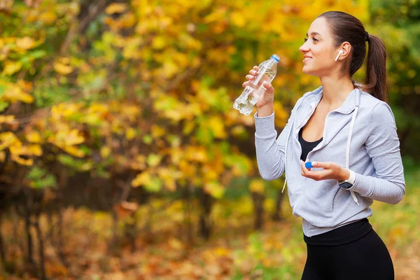 Fitness Girl. Jeune belle femme en vêtements de sport eau potable dans le parc — Photo