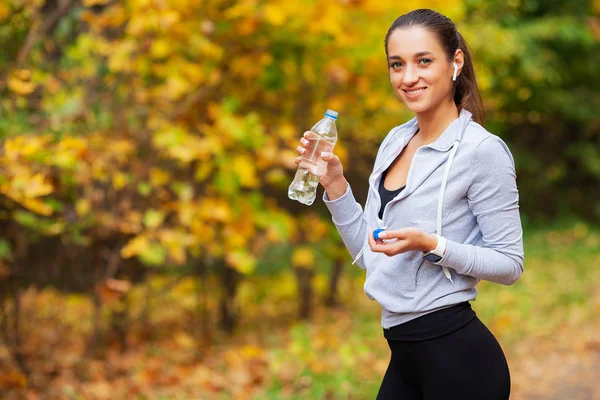 Фитнес-девочка. Молодая красивая женщина в спортивной одежде пьет воду в парке — стоковое фото