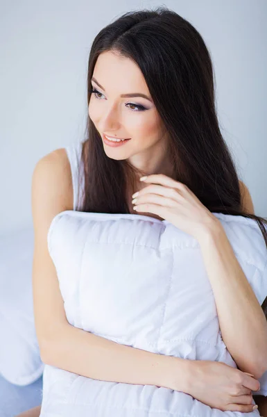 Buenos días. Retrato de una guapa morena sonriente relajándose en la cama blanca — Foto de Stock