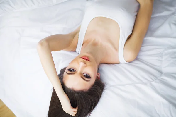 Šťastné ráno. Portrét usmívající se hezká mladá brunetka žena v bílé posteli — Stock fotografie