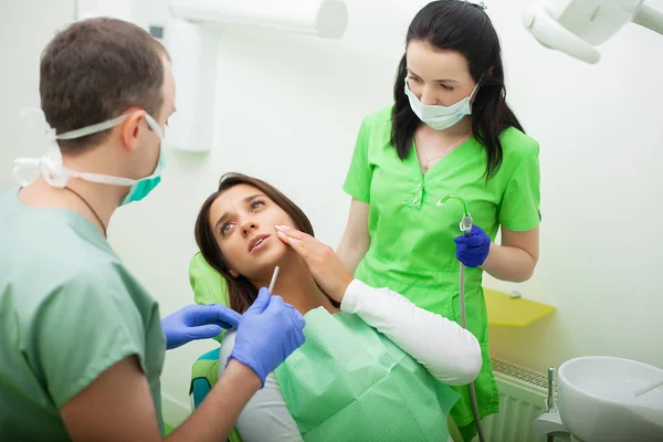 Стоматолог в стоматологічному кабінеті розмовляє з пацієнткою і готується до лікування — стокове фото