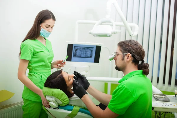 Стоматолог лечит зубы клиенту в стоматологическом кабинете. — стоковое фото