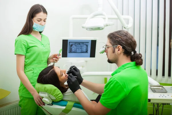 El dentista está tratando los dientes al cliente en el consultorio dental —  Fotos de Stock