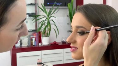 Güzellik Salonu. Sandalyede oturan genç güzel kız modeli. Makyaj sanatçısı makyaj kız yapar
