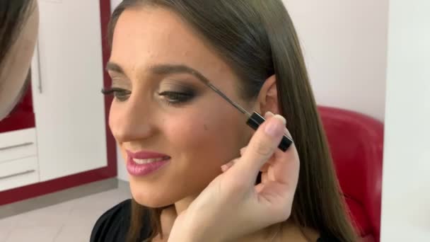 Kadeřnictví. Mladá krásná dívčí modelka sedí v křesle. Make-up dělá ženský. — Stock video