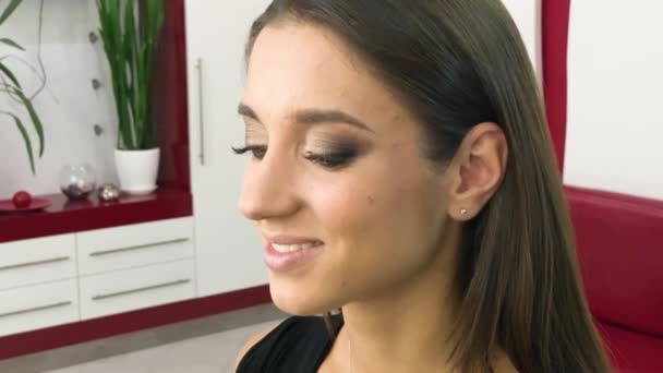 Salón de belleza. Joven modelo hermosa chica sentada en la silla. Maquillaje artista hace maquillaje niñas — Vídeos de Stock