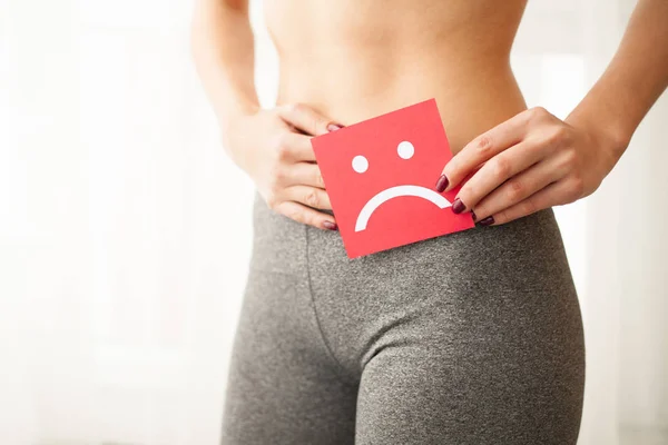 Vajinal veya üriner enfeksiyon ve sorunları kavramı. Genç kadın kağıt Hüzünlü gülümseme ile kasık üzerinde tutar.