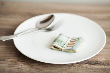 Çatalla tabakta yatan para. Dolar fotoğrafı. Açgözlü yolsuzluk kavramı. Rüşvet fikri