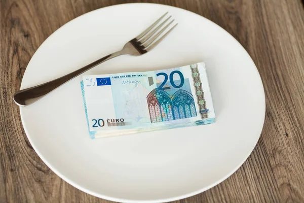 Money lying on the plate with fork. Euros photo. Greedy corruption concept. Bribe idea
