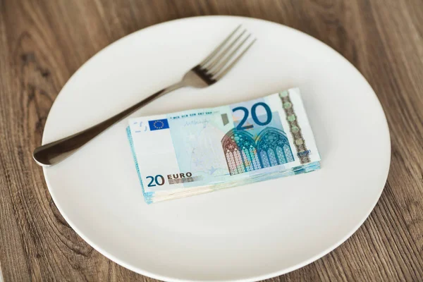 Money lying on the plate with fork. Euros photo. Greedy corruption concept. Bribe idea