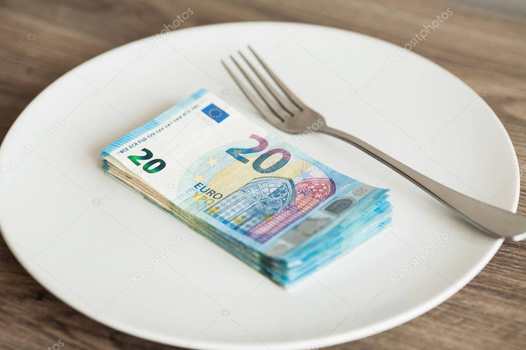 Money lying on the plate with fork. Euros photo. Greedy corruption concept. Bribe idea