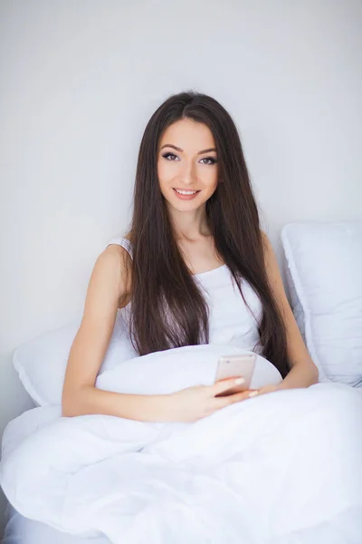 Relajarse en la cama durante el fin de semana. Hermosa mujer relajándose en una cama y luciendo feliz — Foto de Stock