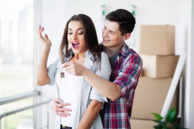 Genç mutlu çift yeni evlerine taşınıyor. Bavulları açıp yeni evi temizliyorlar.