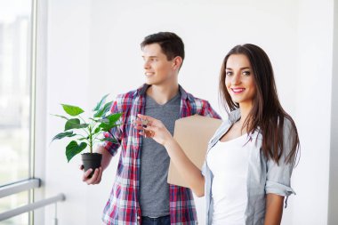 Genç mutlu çift yeni evlerine taşınıyor. Bavulları açıp yeni evi temizliyorlar.