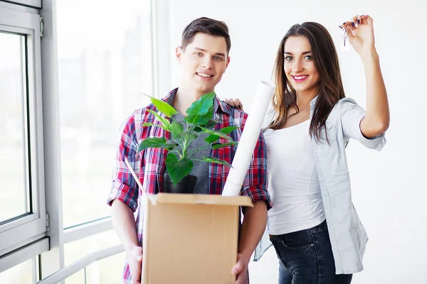 Unga lyckliga par flyttar in i sitt nya hem. De packar upp och städar upp nytt hem — Stockfoto