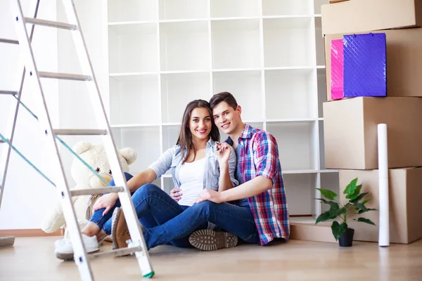 Joven pareja feliz mudarse a su nuevo hogar. Desempaquetan y limpian nuevo hogar — Foto de Stock