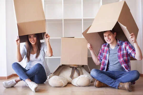 Unga lyckliga par flyttar in i sitt nya hem. De packar upp och städar upp nytt hem — Stockfoto