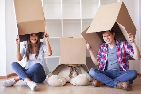 Unga lyckliga par flyttar in i sitt nya hem. De packar upp och städar upp nytt hem — Stockfoto