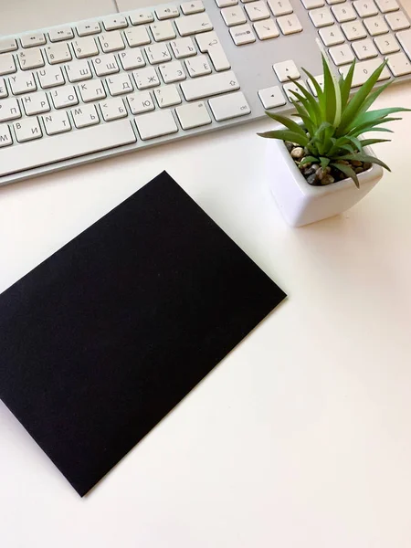 Black single envelope on a natural white table. Top view, copy space