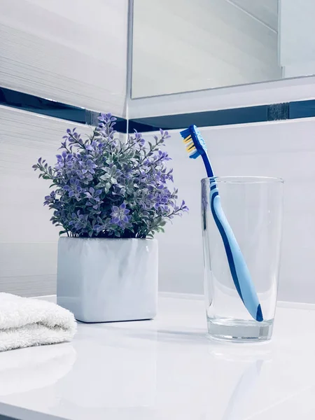 Clean toothbrush in a clear glass on bathroom countertop — Stock Photo, Image