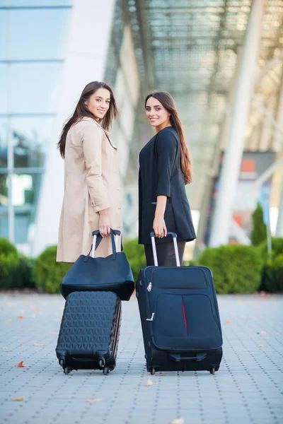 Dwie dziewczyny szczęśliwy podróżujących za granicę razem, niosąc walizki bagaż w Lotnisko — Zdjęcie stockowe