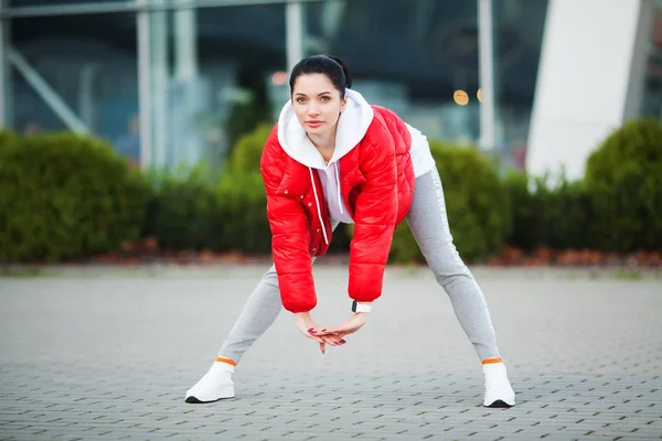 Chica de fitness. Mujer deportiva joven que se extiende en la ciudad moderna. Un estilo de vida saludable en la gran ciudad —  Fotos de Stock