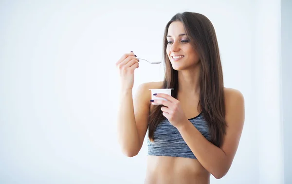 Диета. Счастливая молодая женщина ест йогурт на кухне — стоковое фото