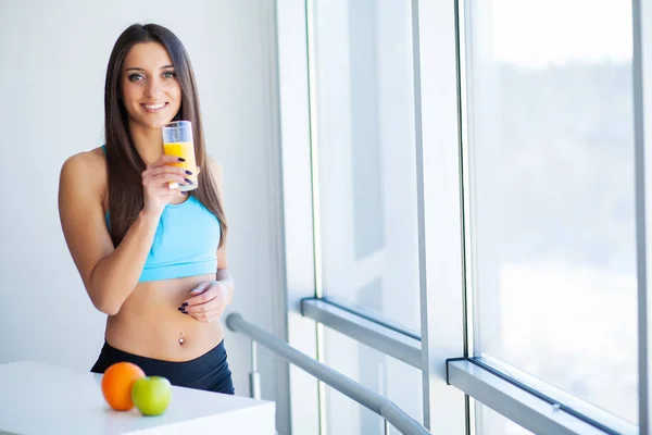 Diet. Happy smiling young woman drinking orange juice