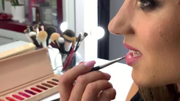 Maquillaje. Primer plano de imágenes en cámara lenta de artista de maquillaje profesional aplicando maquillaje en la cara modelos antes de desfile de moda — Vídeos de Stock