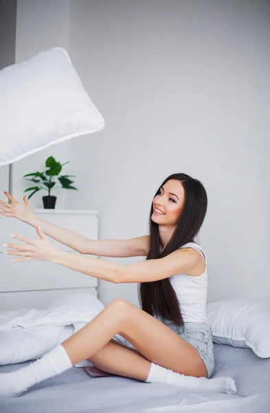 Schattige vrouw glimlachend in bed op wit kussen na slaap of NAP — Stockfoto