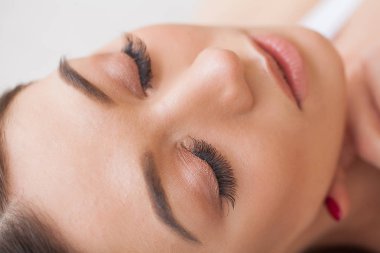 Kirpiklerini uzat. Sahte kirpikler. Kirpik uzatma prosedürü. Profesyonel stilist, kadın kirpiklerini uzatıyor. Usta ve bir müşteri güzellik salonunda.