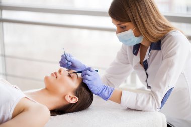 Kirpiklerini uzat. Sahte kirpikler. Kirpik uzatma prosedürü. Profesyonel stilist, kadın kirpiklerini uzatıyor. Usta ve bir müşteri güzellik salonunda.