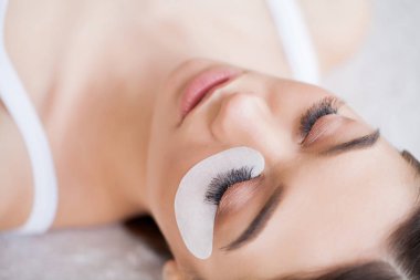 Kirpiklerini uzat. Sahte kirpikler. Kirpik uzatma prosedürü. Profesyonel stilist, kadın kirpiklerini uzatıyor. Usta ve bir müşteri güzellik salonunda.