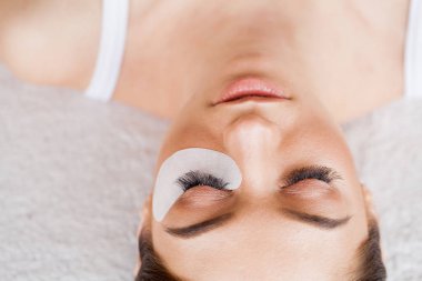 Kirpiklerini uzat. Sahte kirpikler. Kirpik uzatma prosedürü. Profesyonel stilist, kadın kirpiklerini uzatıyor. Usta ve bir müşteri güzellik salonunda.
